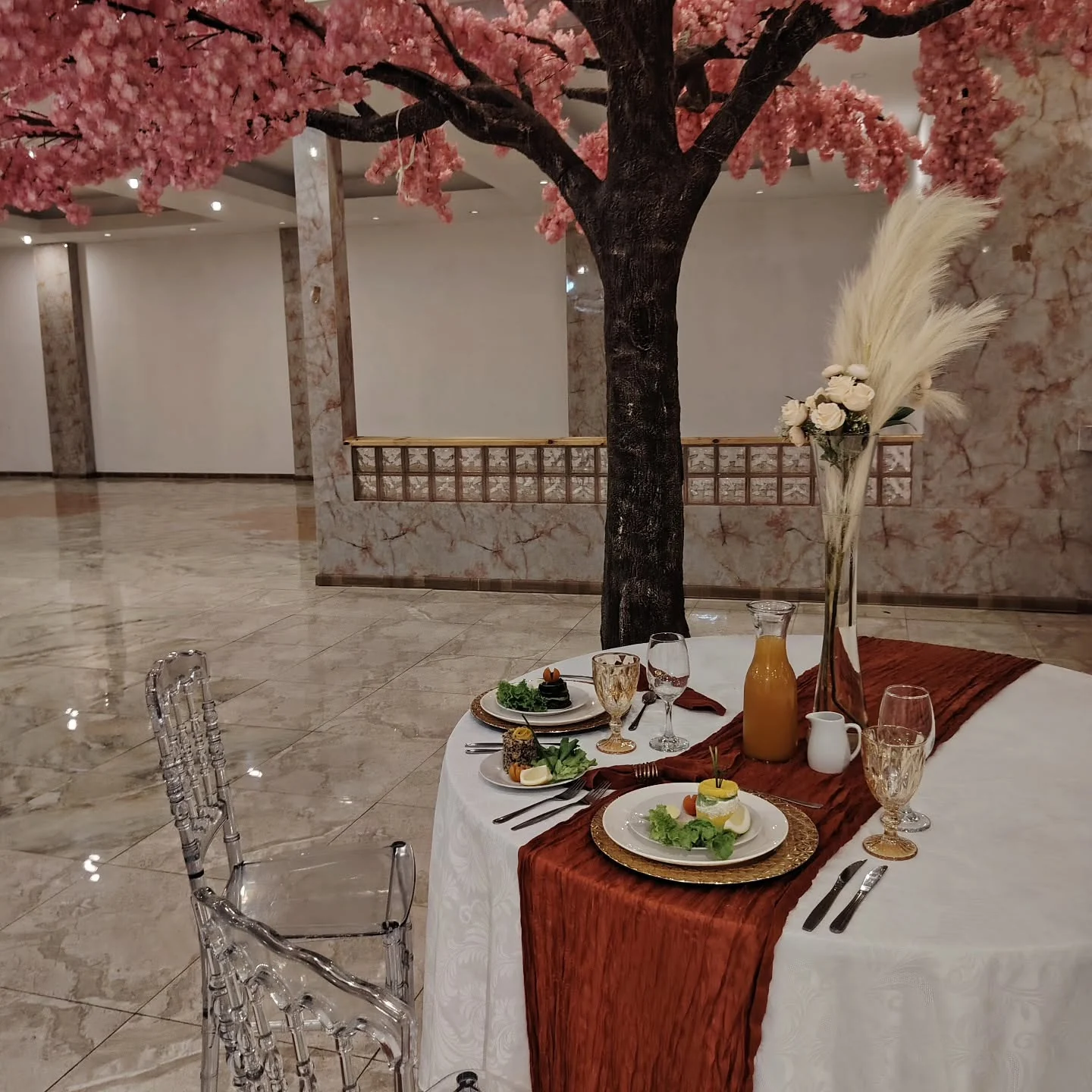 Mesa decorada junto a árbol floral para una celebración