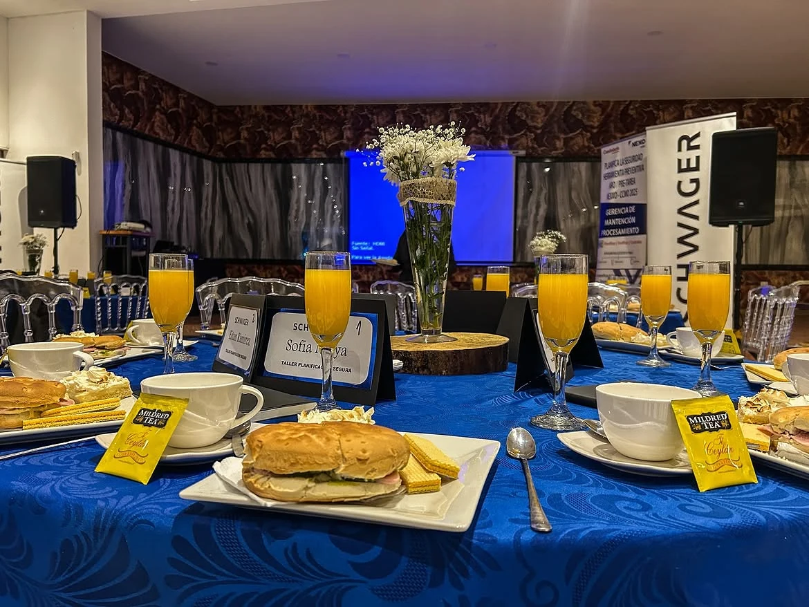Montaje de evento con mesas servidas y pantalla al fondo