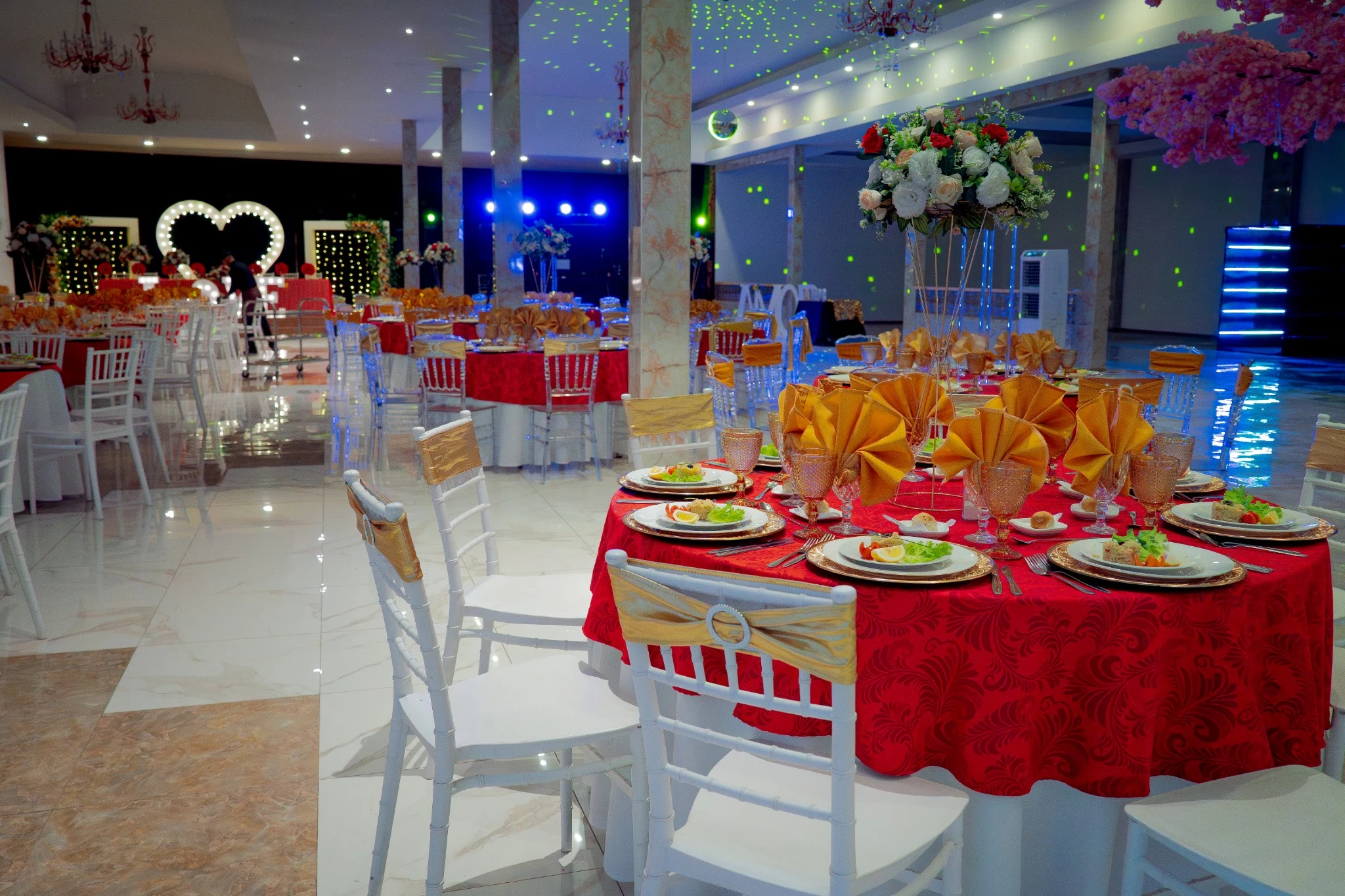 Vista general de salón montado con mesas rojas, iluminación y letras LOVE
