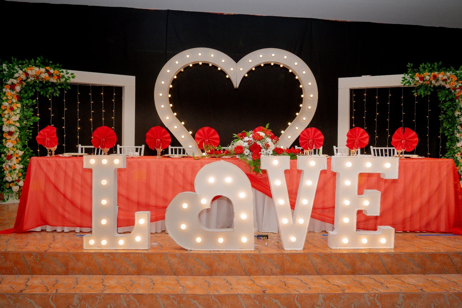 Escenario de matrimonio con letras LOVE iluminadas y corazón de fondo